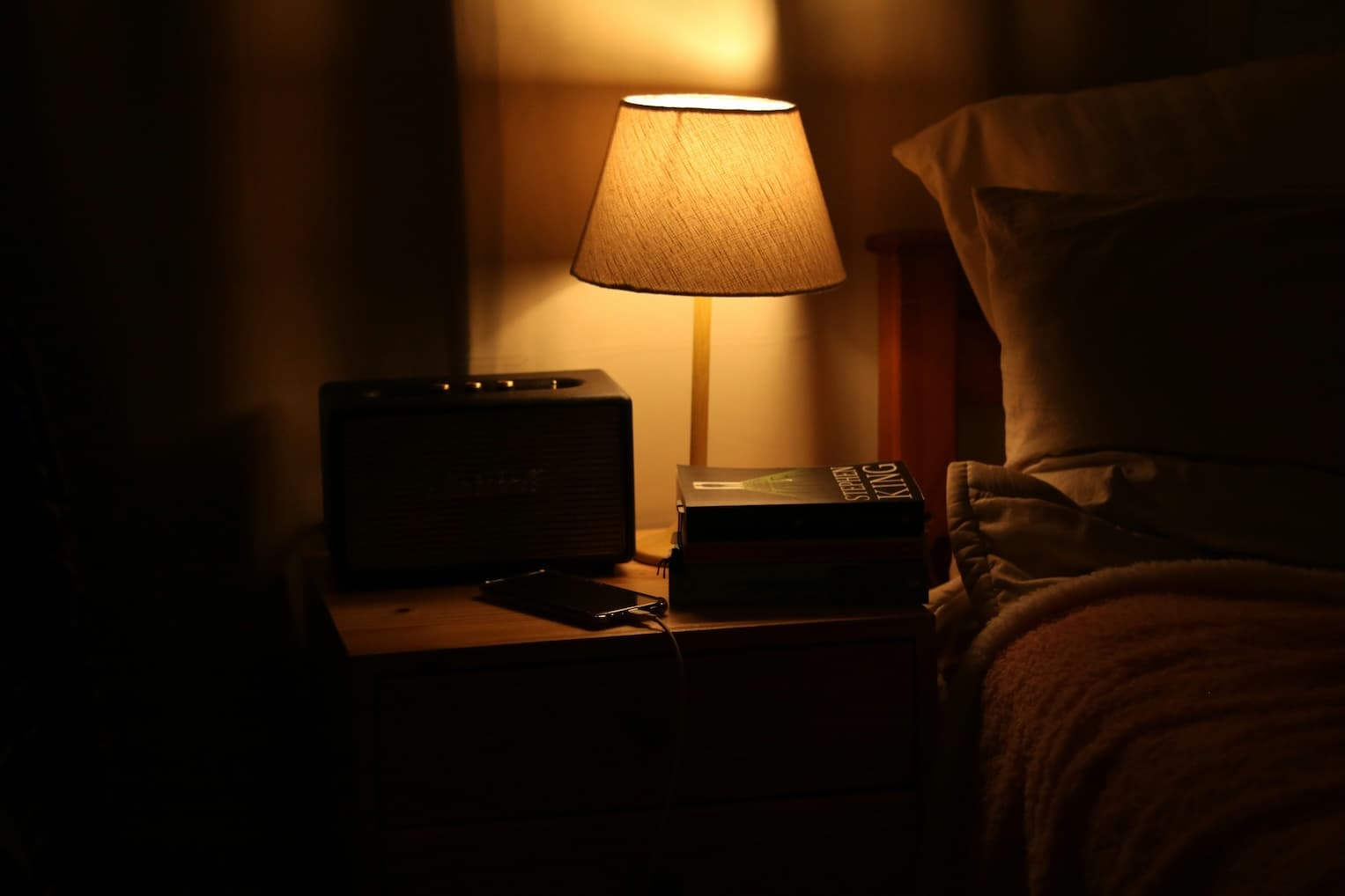 Bedside lamp illuminating a nightstand with a book on it