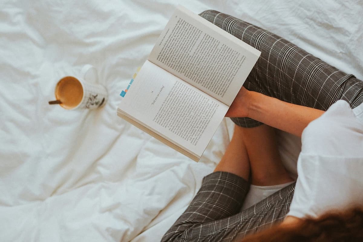 Person reading a book with a cup of coffee