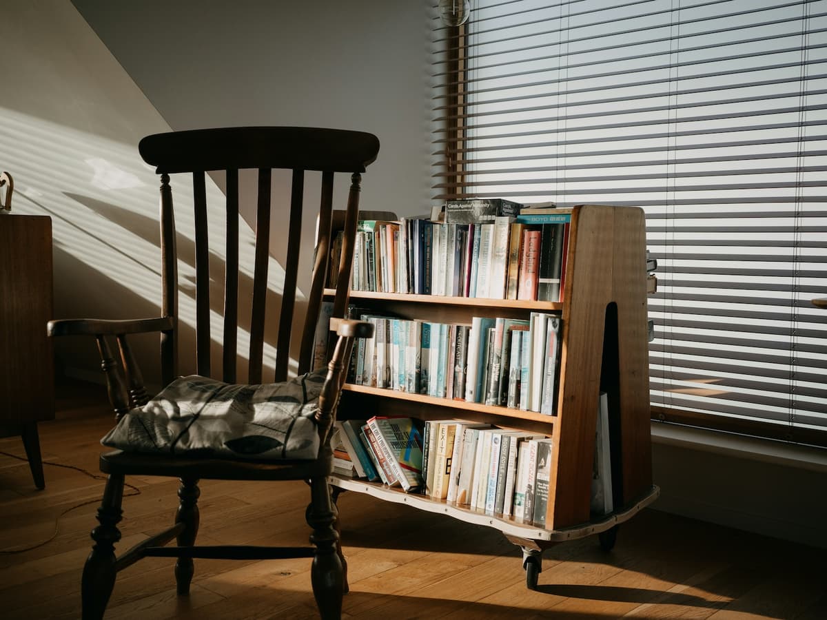 Cozy reading nook with warm lighting, comfortable chair, and a stack of books