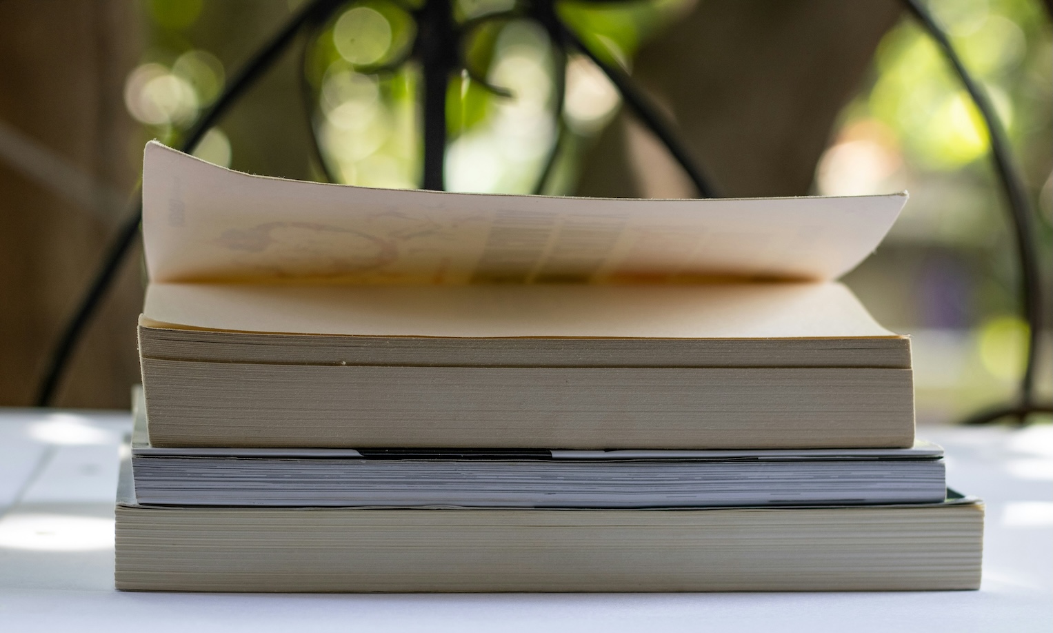 Three books stacked on a table, all in progress of reading