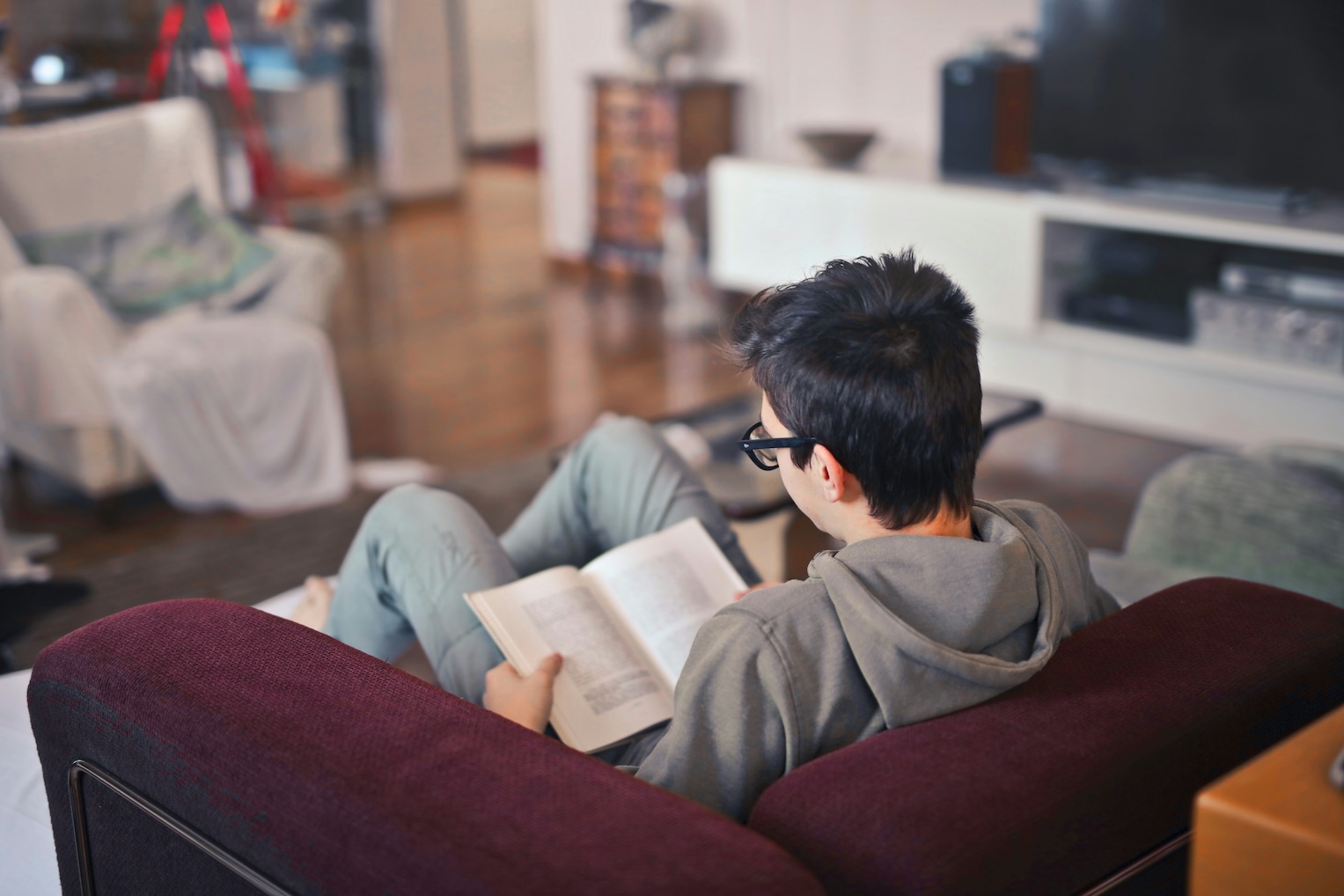 Teenager reading a paperback book on a couch